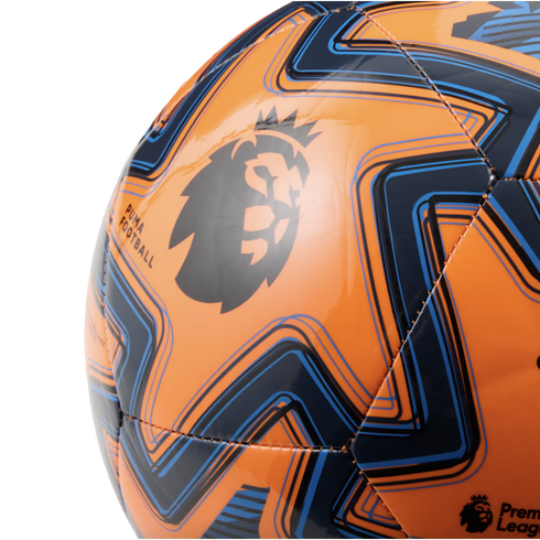 Close-up of an orange Puma Premier League soccer ball featuring navy and light blue geometric patterns on its glossy surface.