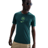 A young man models a dark green Nike Nigeria football shirt with a central crest and tan cargo pants against a white background.