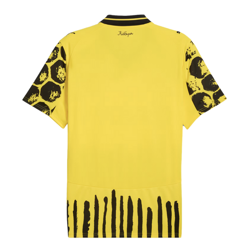 Back of a yellow jersey featuring black-patterned sleeves, vertical stripes at the hem, and 'KidSuper' text near the collar. Small Puma logos are visible on the shoulders.