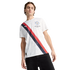 A man wearing a white Manchester City jersey with a navy and red diagonal stripe and black pants, standing against a white background.