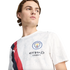 A young man looking to the side while wearing a white Manchester City jersey featuring a red and blue diagonal sash.