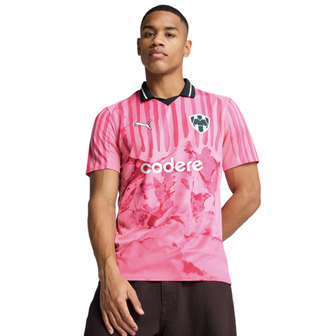 A man wears a pink Puma soccer jersey featuring a black collar, "codere" logo, and a marbled graphic pattern against a plain white background.