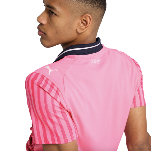 Side profile of a person wearing a pink Puma jersey with red striped sleeves and a navy blue collar. The jersey features a white Puma logo and "KidSuper" text on the back.