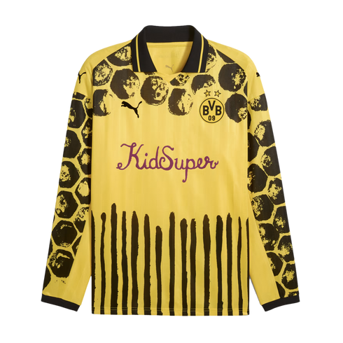 Yellow long-sleeved Puma x KidSuper BVB jersey with black splattered shoulder patterns, vertical black stripes at the hem, and a purple script "KidSuper" logo on the chest.