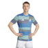 A man wearing a blue and green patterned Real Madrid football shirt and white shorts stands with his hands on his hips against a white background.