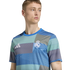 Man wearing a blue and green patterned Real Madrid soccer jersey with the Adidas logo.