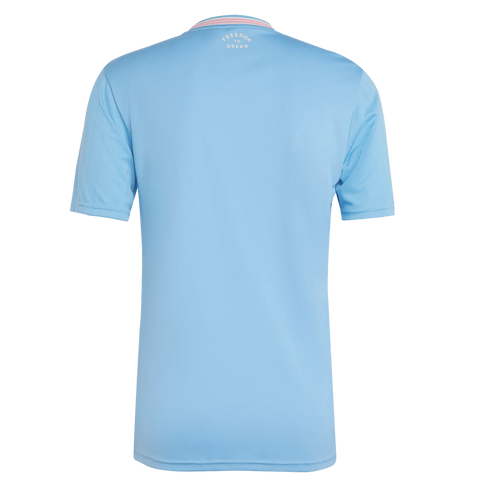 The back of a light blue short-sleeved jersey featuring a striped collar and white "FREEDOM TO DREAM" text printed at the nape of the neck.