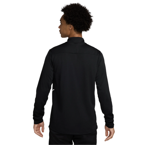 A back view of a person with dark, curly hair wearing a long-sleeved black athletic top against a white background.
