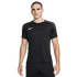 A man stands against a plain white background wearing a black Nike t-shirt with grey shoulder panels and black shorts.
