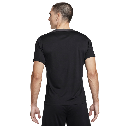 Back view of a man wearing a black short-sleeved athletic t-shirt and matching shorts against a plain white background.