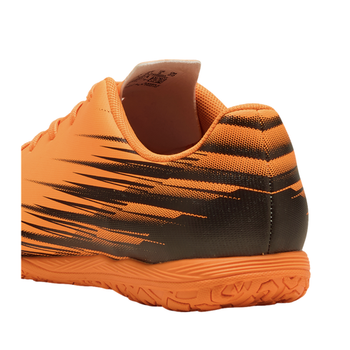Rear-side view of an orange and black athletic shoe with graphic patterns and a textured sole, set against a solid black background.