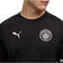 A person wearing a black Manchester City football shirt with a white Puma logo and the club's monochrome crest on the chest.
