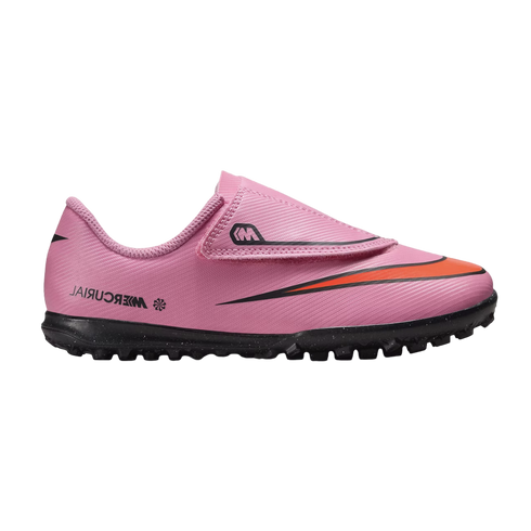 A pink Nike Mercurial turf soccer shoe with a velcro strap and orange swoosh, set against a black background.
