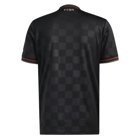 Back of a black sports jersey with a tonal checkered pattern. Features red and green trim on the sleeves and collar, and white "FCBM" lettering on the upper back.