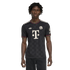 Man wearing a black Bayern Munich soccer jersey with white logos and red and green trim on the collar and sleeves, against a black background.