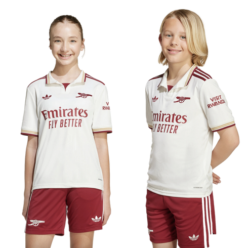 A girl and a boy smiling while wearing white and maroon Arsenal football kits against a black background.
