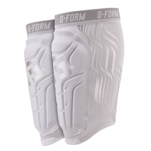 A pair of white and silver G-Form shin guards with grey elastic bands, featuring SmartFlex padding, set against a black background.