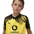 A young boy wearing a yellow and black Borussia Dortmund Puma soccer jersey with a Vodafone sponsor logo against a black background.