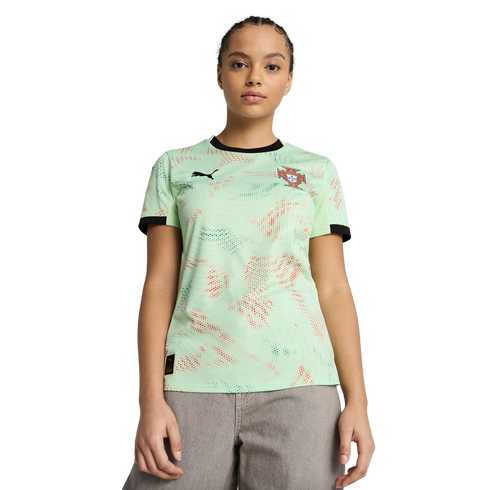 A woman in a mint green Portugal football jersey with a red and green pattern and grey pants, posing against a solid black background.