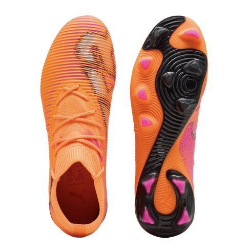 Top and bottom views of bright orange Puma soccer cleats featuring black textured stripes and pink-tipped studs on the sole.