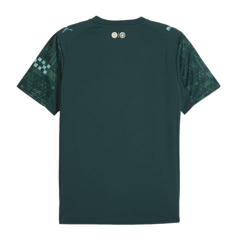 The back of a dark teal Manchester City soccer jersey featuring geometric patterned sleeves and light blue Puma logos on the shoulders.