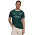 A man modeling a dark green Manchester City jersey with geometric patterns and light green trim, standing against a black background.