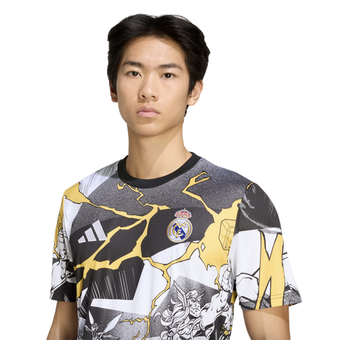 A young man wearing a Real Madrid t-shirt featuring comic-style graphics and yellow lightning bolts against a solid black background.