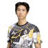 A young man wearing a Real Madrid t-shirt featuring comic-style graphics and yellow lightning bolts against a solid black background.