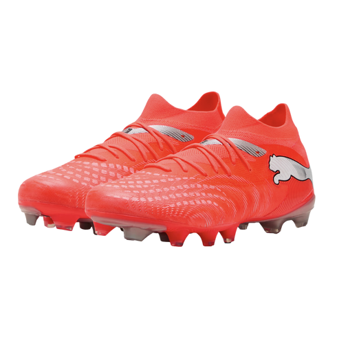 A pair of vibrant orange Puma soccer boots with silver logo accents and textured uppers, shown from a three-quarter view against a black background.