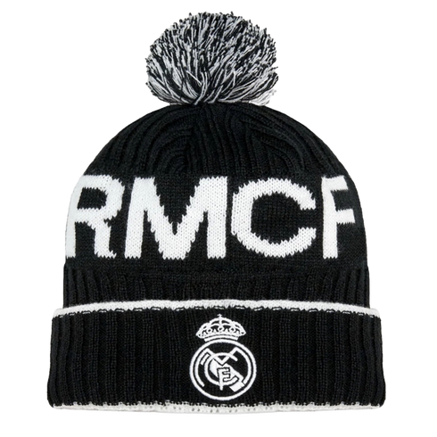 A black knit beanie featuring 'RMCF' in large white letters and the Real Madrid club crest on the folded cuff, topped with a black and white pom-pom.