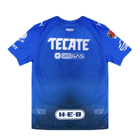 Back of a blue Rayados soccer jersey with white sponsor logos for TECATE, OXXO GAS, and H-E-B. The fabric features a blue gradient that fades to dark at the hem.