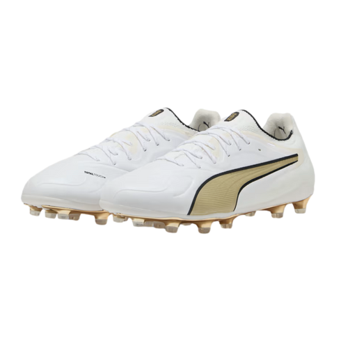 A pair of white Puma soccer cleats with gold logos and matching gold studs, displayed against a black background.