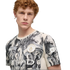 A young man with curly red hair wearing a grey and white patterned Manchester City soccer jersey against a black background.