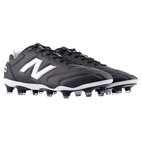 A pair of black and white New Balance soccer cleats featuring the iconic white "N" logo on the side and a studded outsole, set against a black background.