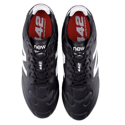 A pair of black New Balance 442 soccer cleats from a top-down perspective, featuring white logos and red insoles with white text.