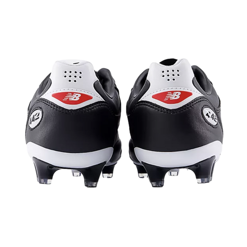 Rear view of black and white New Balance 442 soccer cleats against a black background, featuring red logos on the white heel counters.