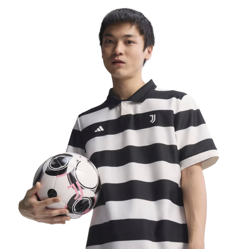 A man in a black and white striped Juventus polo shirt holding a soccer ball against a black background.