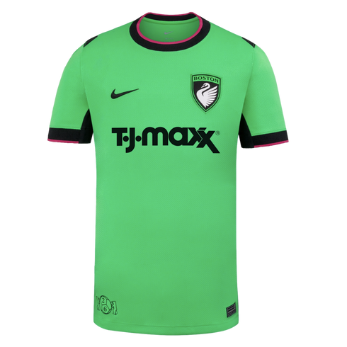 A bright green Nike soccer jersey featuring a T.J.Maxx sponsor logo, a Boston swan crest, and black and pink trim on the collar and sleeve cuffs.