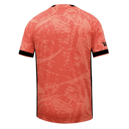 Back view of a salmon-pink jersey with an abstract tonal pattern, black sleeve cuffs, and thin black side stripes on a black background.