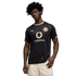 A man with glasses and curly hair wears a black and gold Borussia Dortmund soccer jersey with a Vodafone logo, posing against a black background.