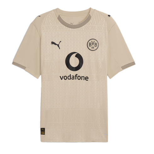 Beige Puma soccer jersey with a black BVB crest and Vodafone logo. Subtle geometric patterns cover the shirt, which has striped details on the collar and cuffs.