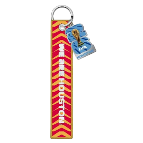 A FIFA World Cup 2026 keychain featuring a red and yellow fabric strap with the text "WE ARE HOUSTON" and a blue "26" charm with the World Cup trophy.