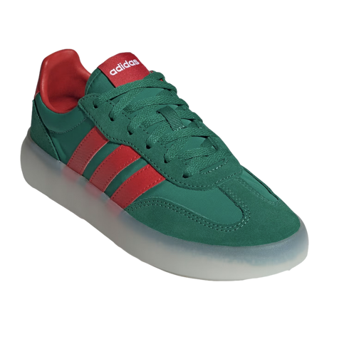 A three-quarter view of a dark green suede Adidas sneaker with three red leather stripes and a thick, translucent white sole, set against a solid black background.