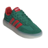 A three-quarter view of a dark green suede Adidas sneaker with three red leather stripes and a thick, translucent white sole, set against a solid black background.