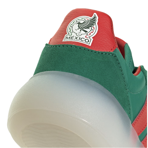 A close-up of the heel of a green and red sneaker featuring a thick translucent sole and a patch of the Mexico national soccer team logo.