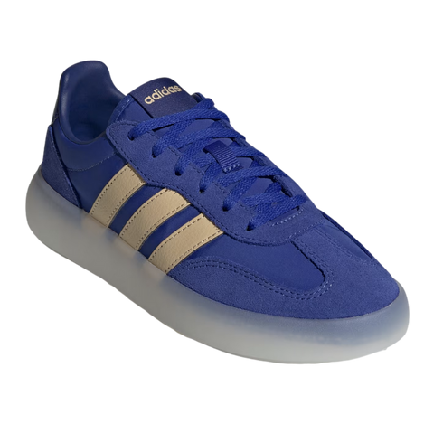 An angled view of a royal blue Adidas sneaker featuring light tan side stripes and a thick, translucent white platform sole, set against a solid black background.