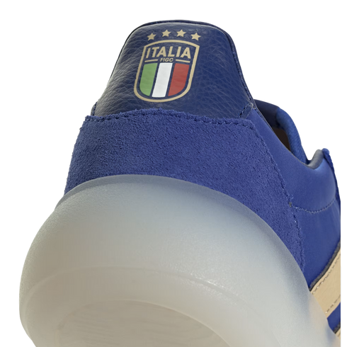 A close-up view of the heel of a blue sneaker, featuring the Italian national football team (FIGC) crest embroidered on pebbled leather above a chunky, translucent white rounded sole.