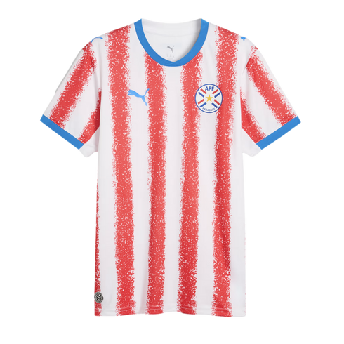 White football jersey with red spray-painted vertical stripes, blue collar and sleeve cuffs, blue Puma logo, and the APF Paraguay national team crest.