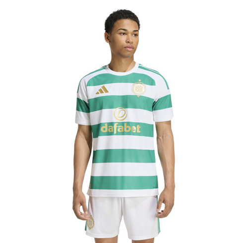 A young man modeling a green and white horizontal striped football jersey with gold logos and matching white shorts against a plain white background.