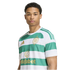 A young man wearing a green and white striped Celtic FC soccer jersey with gold logos against a plain white background.